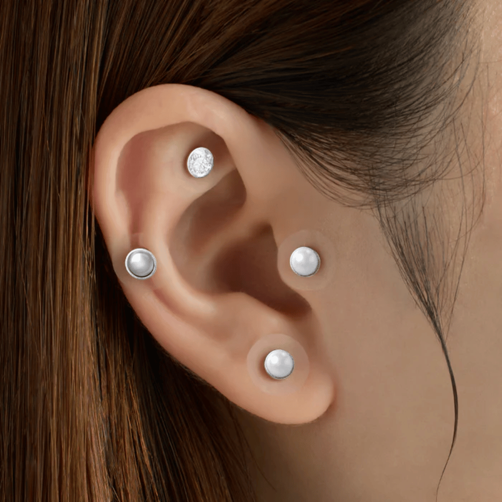 Primo piano di un orecchio con diversi RETURNITY Ear Therapy Acupressure Patch applicati su diverse aree dell'orecchio per l'agopressione e un look elegante.