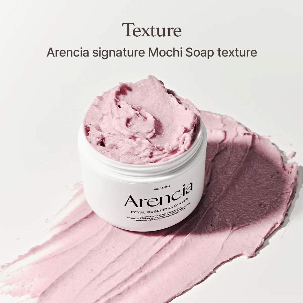 Barattolo con Arencia Royal Rosehip Cleanser visibile sopra un detergente rosa spalmato con una texture simile a mochi. Il testo sopra descrive il prodotto come la texture firma di Arencia.