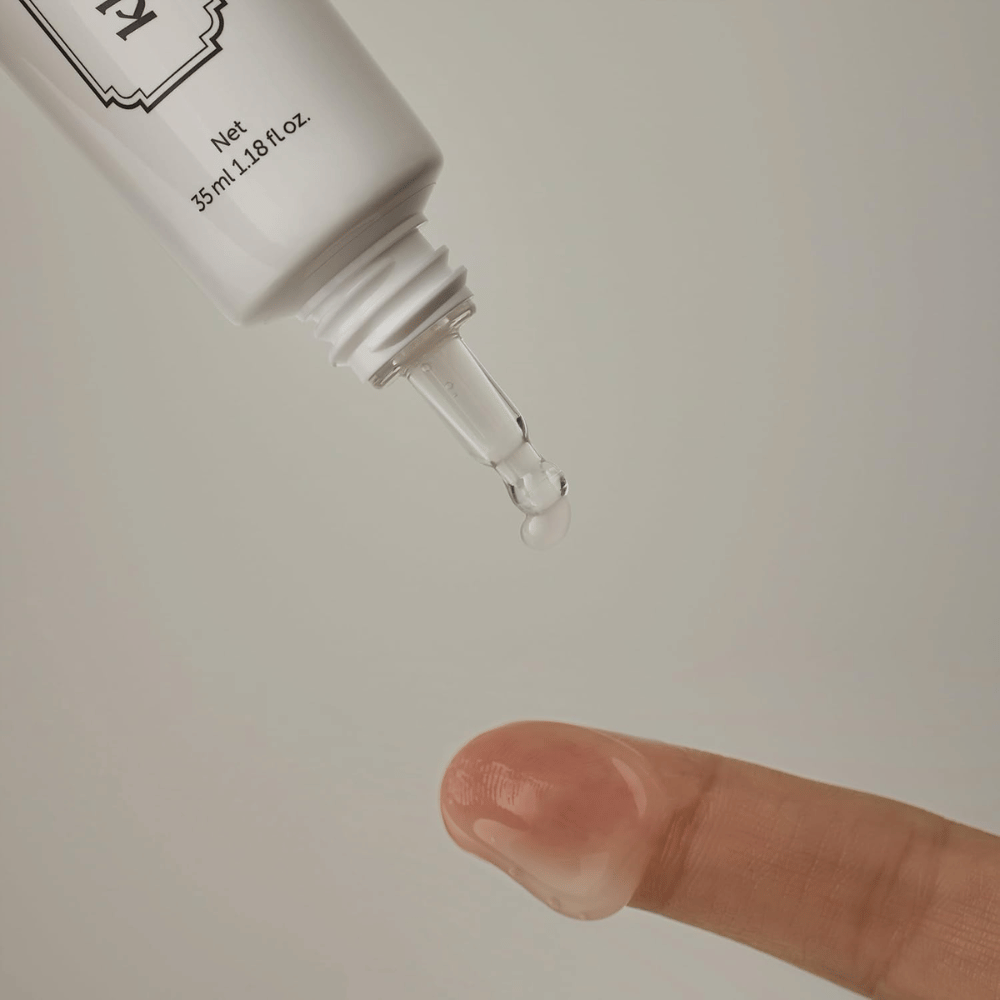 Immagine di dettaglio in cui un gel chiaro e leggero viene applicato dalla punta sottile su un dito. L’immagine illustra la consistenza trasparente a base di gel del prodotto e l’applicazione precisa intorno alla zona degli occhi.