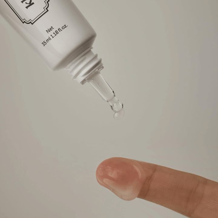 Immagine di dettaglio in cui un gel chiaro e leggero viene applicato dalla punta sottile su un dito. L’immagine illustra la consistenza trasparente a base di gel del prodotto e l’applicazione precisa intorno alla zona degli occhi.