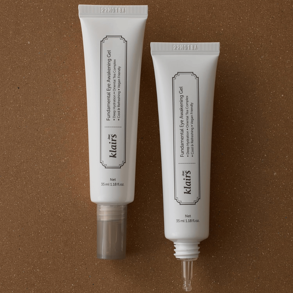 Immagine prodotto che mostra Klairs Fundamental Eye Awakening Gel in due versioni: un tubo chiuso e un tubo aperto che mette in risalto la sottile punta applicatrice. La confezione presenta un design bianco minimalista e sottolinea l’attenzione del prodotto all’idratazione, alla sensazione rinfrescante e alla cura rivitalizzante per la zona degli occhi.