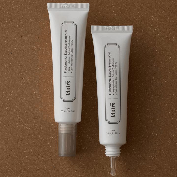 Immagine prodotto che mostra Klairs Fundamental Eye Awakening Gel in due versioni: un tubo chiuso e un tubo aperto che mette in risalto la sottile punta applicatrice. La confezione presenta un design bianco minimalista e sottolinea l’attenzione del prodotto all’idratazione, alla sensazione rinfrescante e alla cura rivitalizzante per la zona degli occhi.