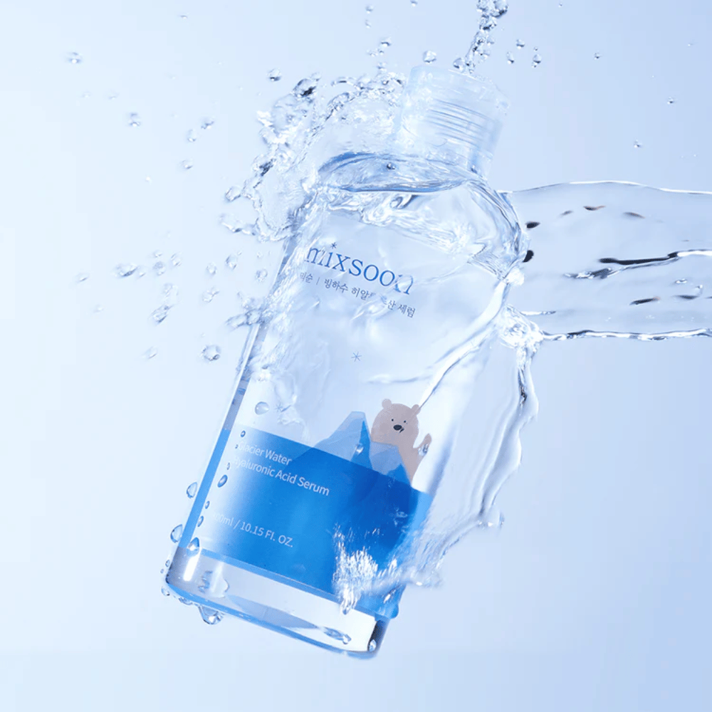 Mixsoon Glacier Water Hyaluronic Acid Serum-bottiglia con etichetta blu e motivo di orso polare circondata da acqua spruzzante su sfondo azzurro.