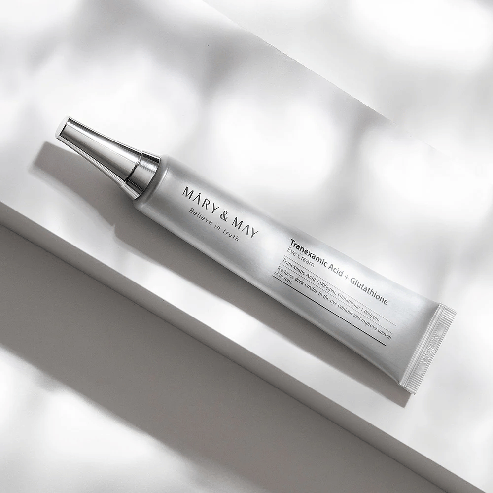Primo piano di Mary&May Tranexamic Acid + Glutathione Eye Cream con applicatore in metallo, sviluppato per illuminare le occhiaie e uniformare il tono della pelle intorno agli occhi.