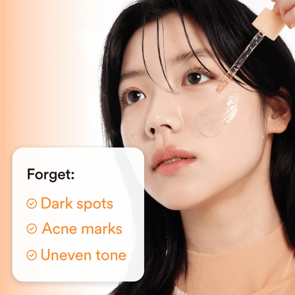 Kvinna applicerar serum med pipett på kinden. Text på bilden listar fördelar: "Forget: Dark spots, Acne marks, Uneven tone".