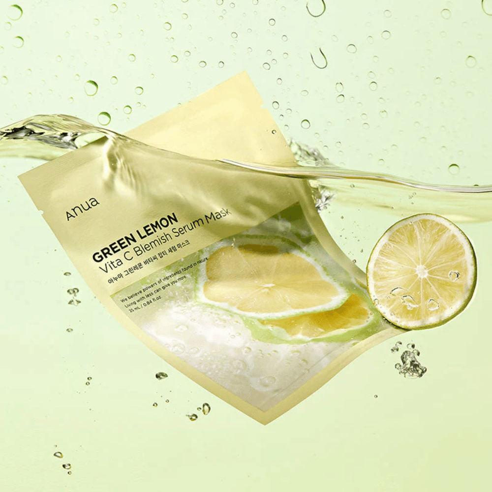 Un'immagine vivace della confezione di Anua Green Lemon Vita C Blemish Serum Mask con gocce d'acqua trasparenti e fette di limone verde intorno. La confezione è parzialmente coperta da un flusso d'acqua su uno sfondo verde chiaro.