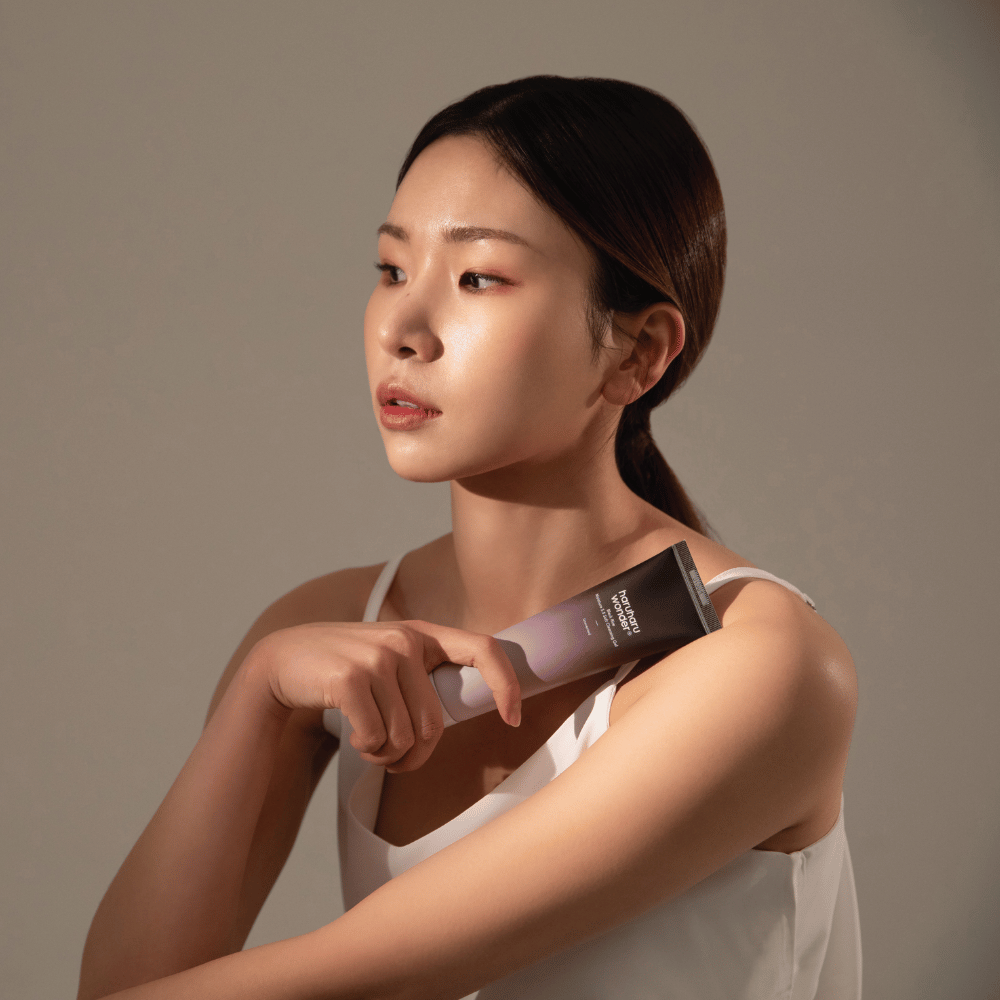 Una giovane donna asiatica che tiene un pennello in mano mentre usa Haruharu Wonders Black Rice Moisture 5.5 Soft Cleansing Gel 100ml.