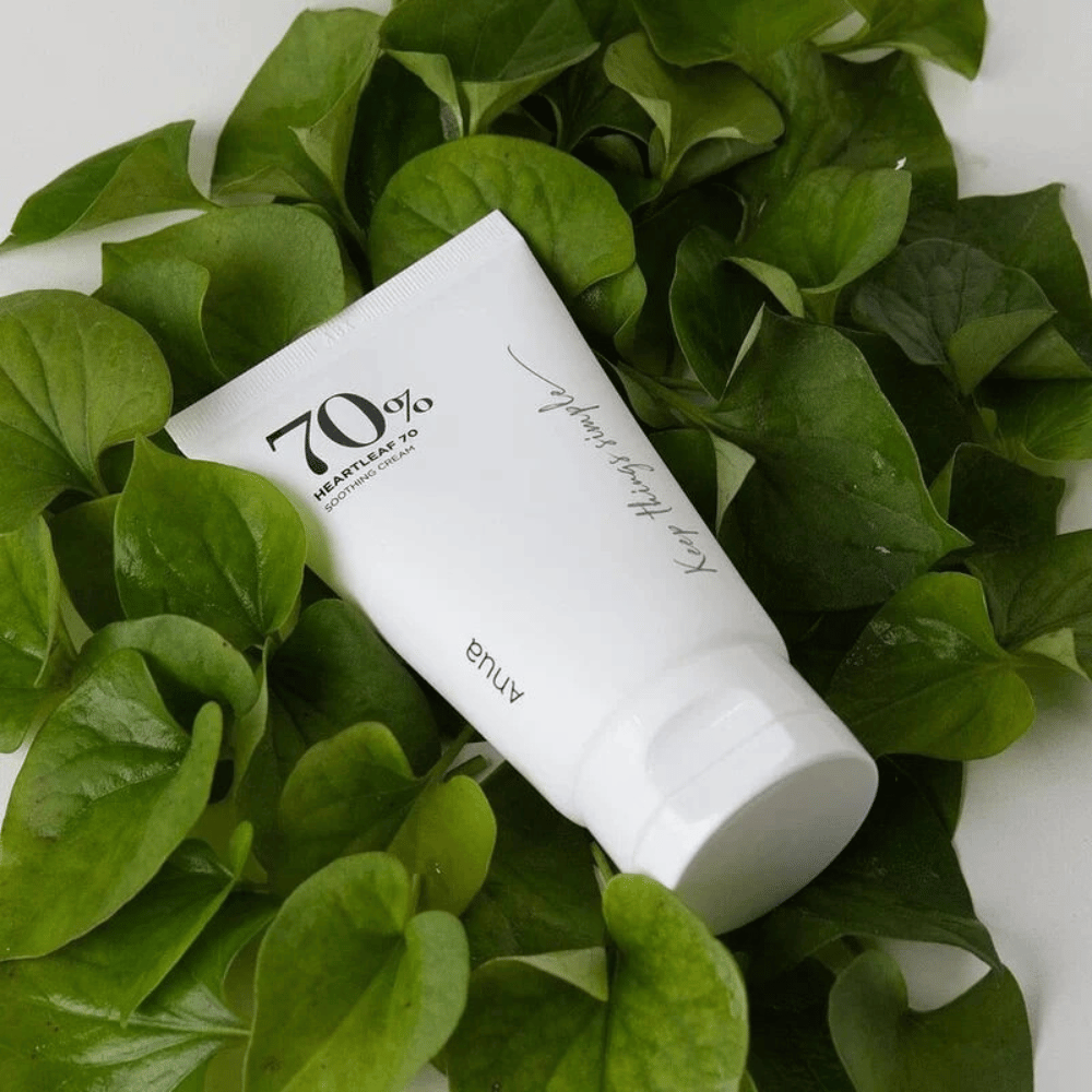 Un tubo di Heartleaf 70% Soothing Cream giace su un letto di foglie verdi.