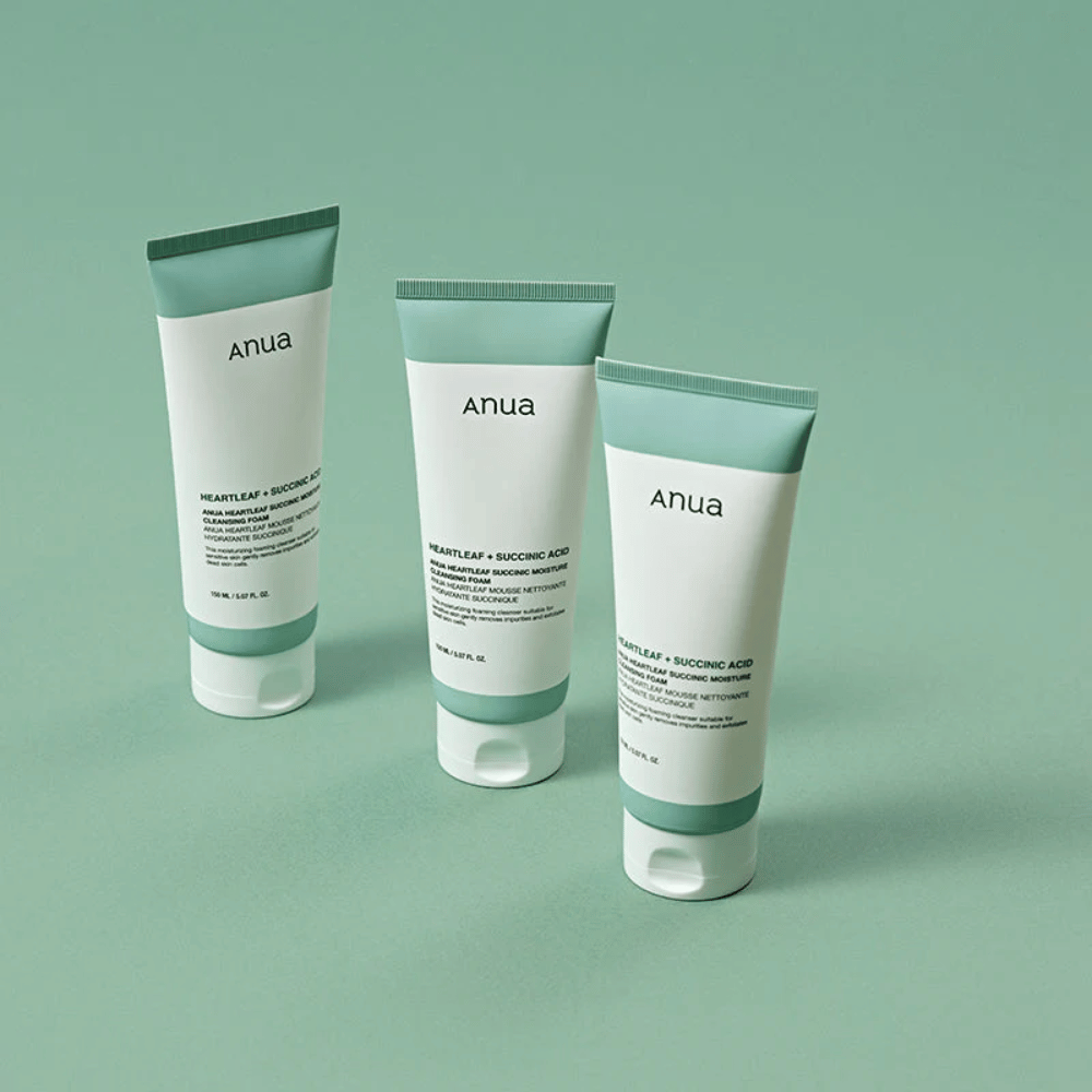Tre confezioni di Anua Heartleaf + Succinic Acid Moisture Cleansing Foam presentate su uno sfondo verde chiaro. L'immagine evidenzia il design pulito e minimalista del prodotto e trasmette un'impressione professionale della linea di prodotti.