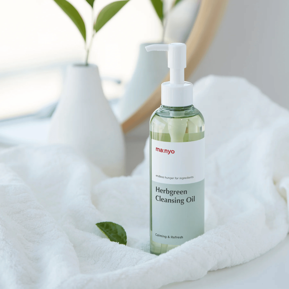 ma:nyo Herbgreen Cleansing Oil in flacone con pompa su asciugamano bianco, calmante olio detergente con ingredienti a base di erbe per delicato detergente viso
