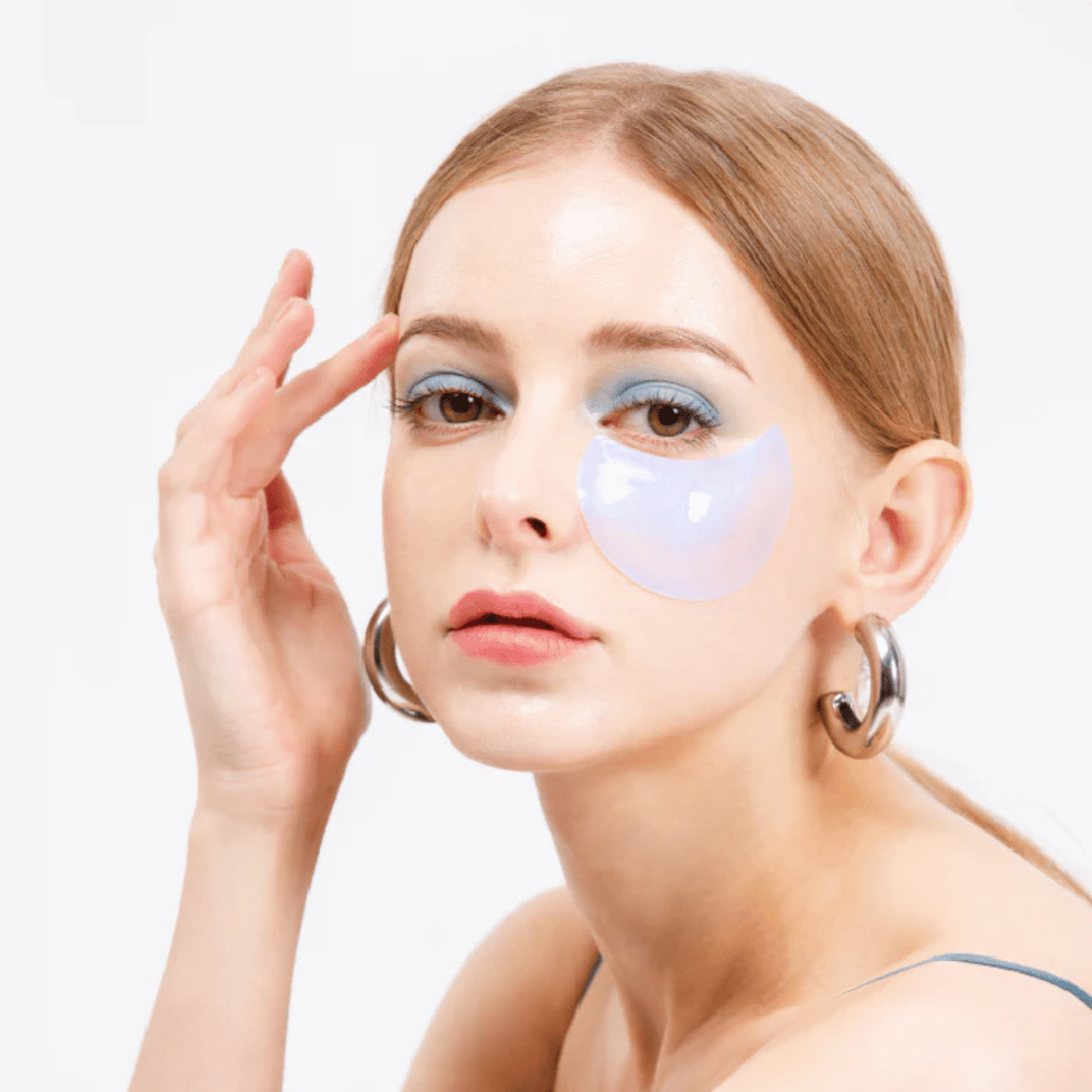 Modello indossa un patch occhi idrogel scintillante blu sotto l'occhio per un effetto rinfrescante.