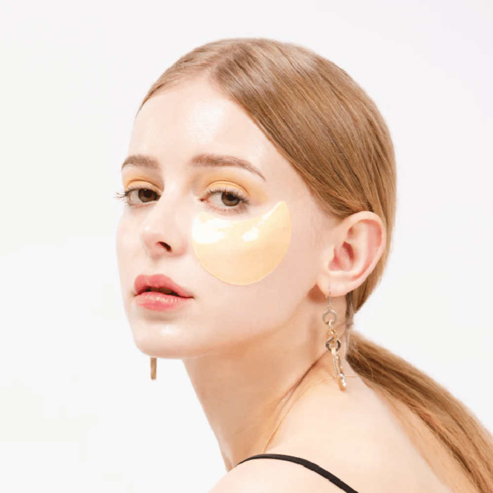 Modello indossa un idrogel dorato scintillante patch occhi sotto l'occhio per un effetto illuminante.