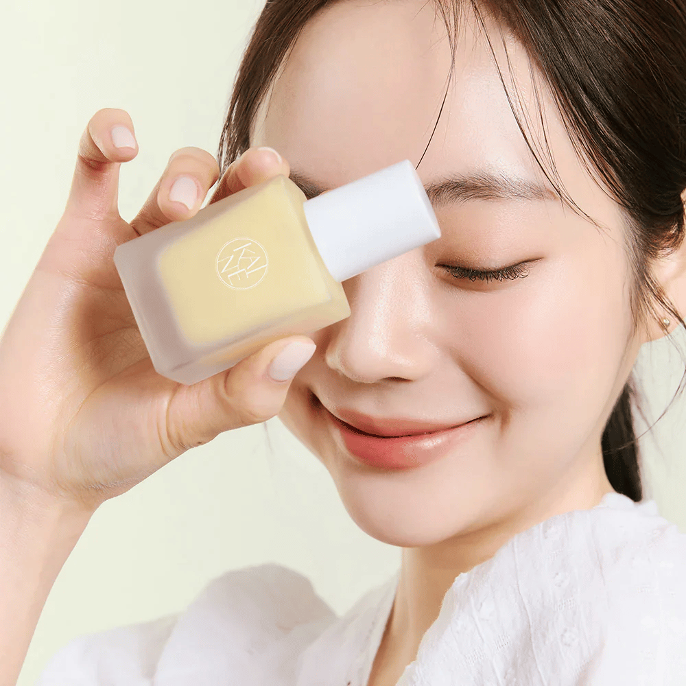 Una donna tiene in mano una bottiglia KAINE Vita Drop Serum da 30ml.