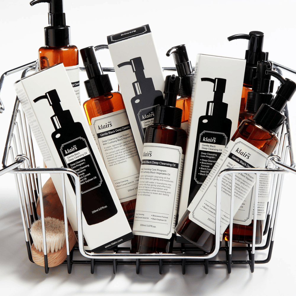 Un mini carrello della spesa pieno di prodotti per la cura della pelle di Klairs, inclusi Gentle Black Deep Cleansing Oil in flaconi trasparenti con pompe nere e confezioni abbinate.