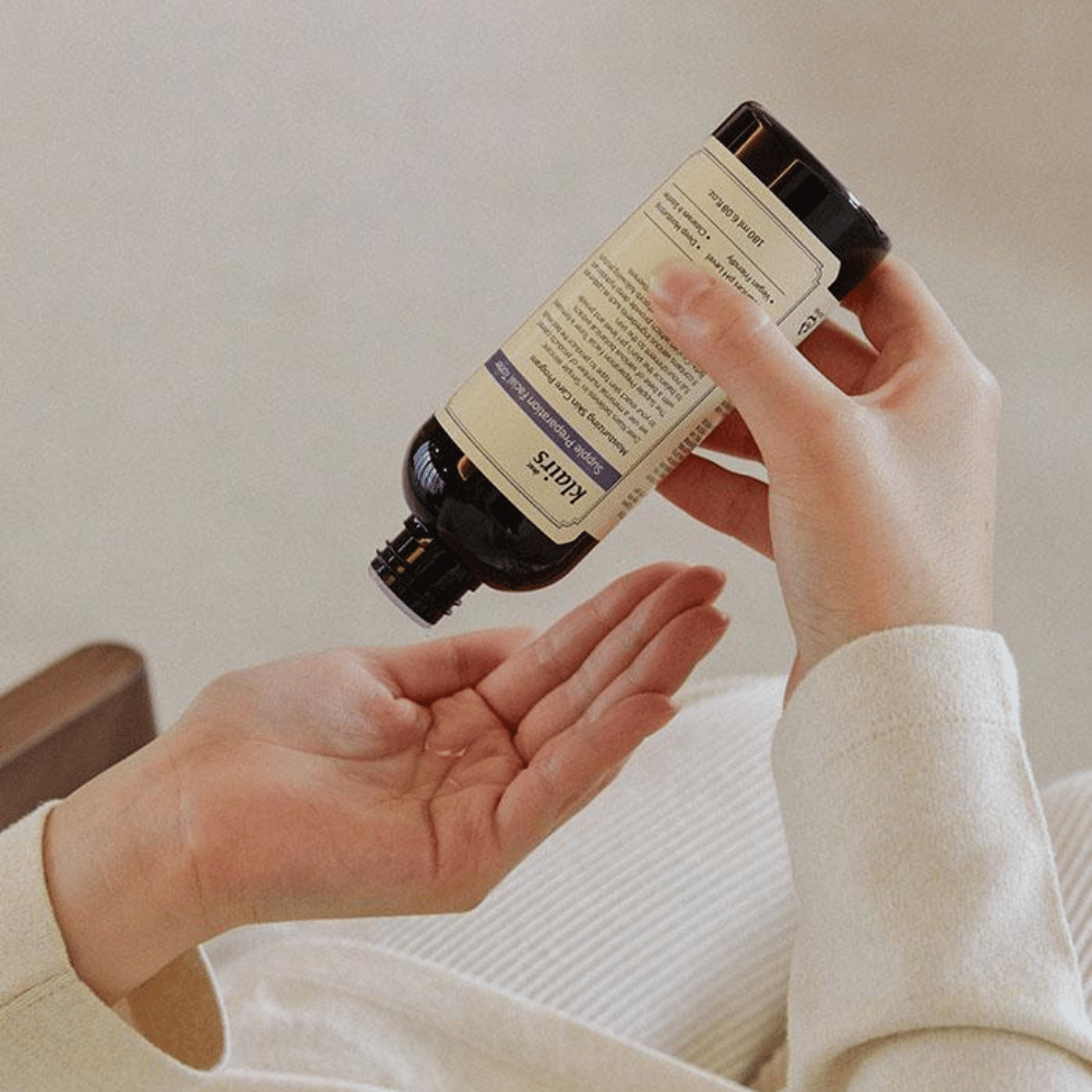 Una persona tiene una bottiglia di Klairs Supple Preparation Facial Toner capovolta sopra la mano, pronta a dosare il prodotto.
