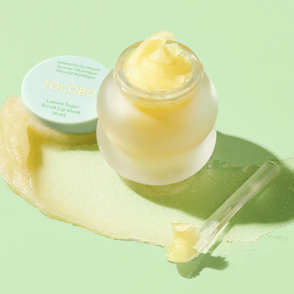 Öppen burk med Tocobo Lemon Sugar Scrub Lip Mask på en grön bakgrund, med innehållet tydligt synligt.