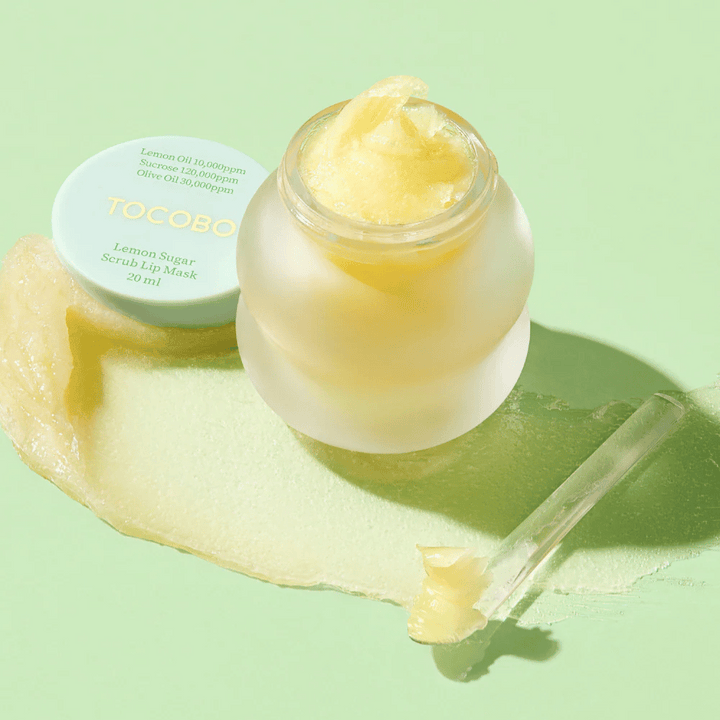 Öppen burk med Tocobo Lemon Sugar Scrub Lip Mask på en grön bakgrund, med innehållet tydligt synligt.