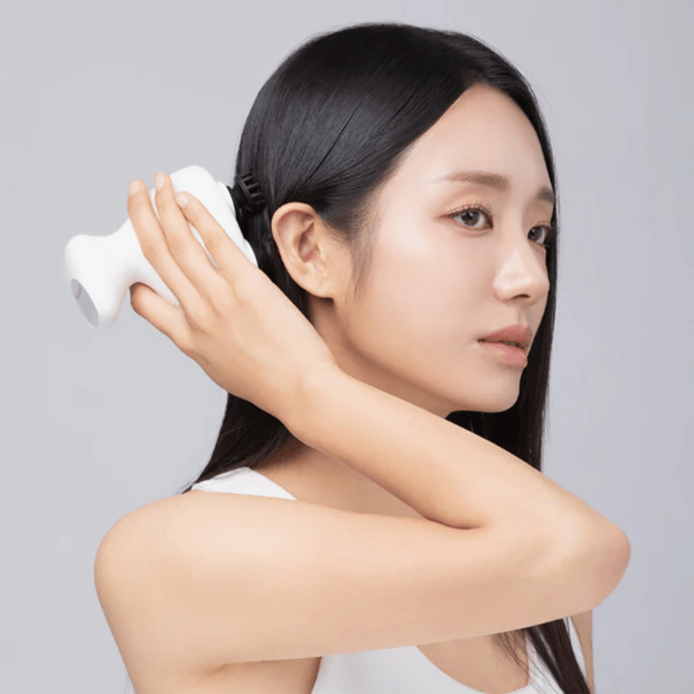 La modella utilizza Beaund Lift Head Spa direttamente sul cuoio capelluto dietro l'orecchio. L'immagine dimostra come il dispositivo venga utilizzato per massaggiare il cuoio capelluto e fornire una piacevole stimolazione.