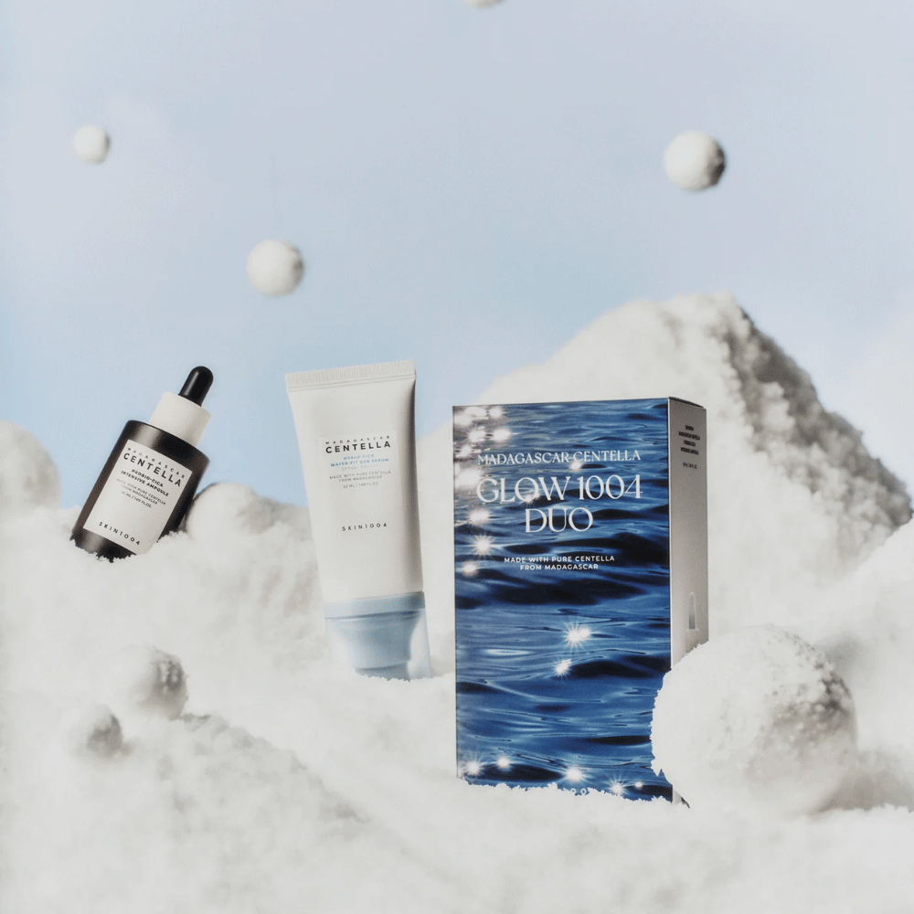 L'immagine mostra il set per la cura della pelle "Madagascar Centella Glow 1004 Duo" da SKIN1004, posizionato su uno sfondo che rappresenta neve e cielo.