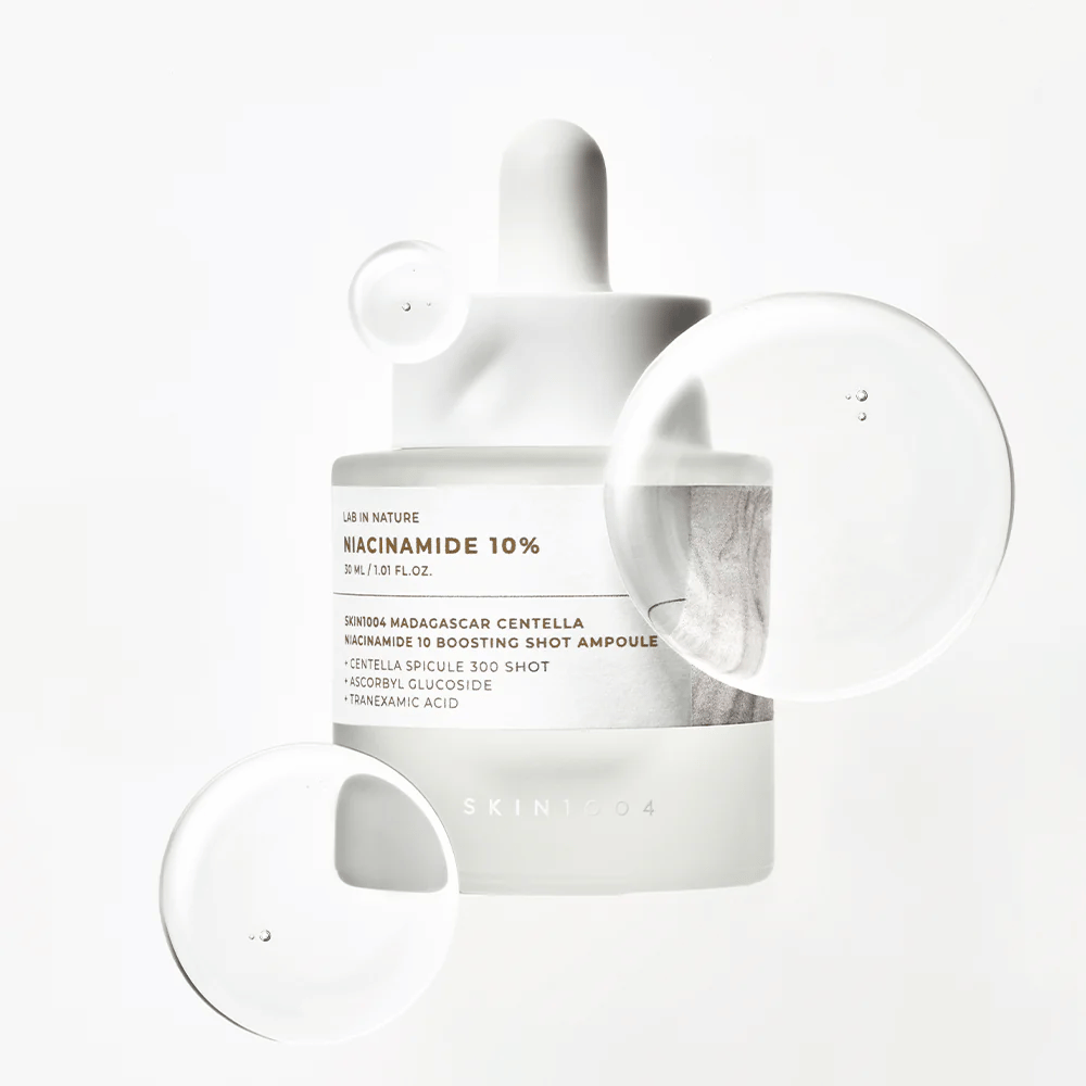 SKIN1004 Madagascar Centella Niacinamide 10 Boosting Shot Ampoule con gocce di siero che mostrano una formula leggera, ad assorbimento rapido con niacinamide, acido tranexamico e centella.