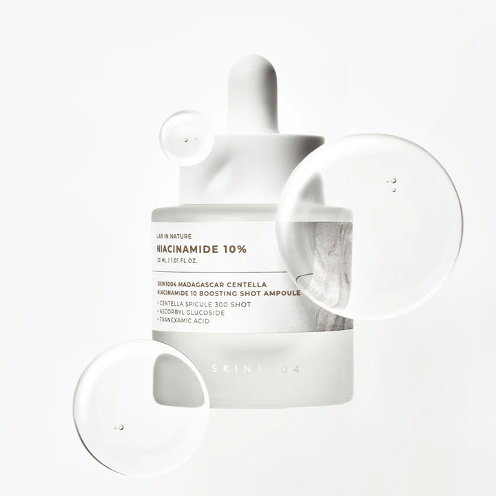 SKIN1004 Madagascar Centella Niacinamide 10 Boosting Shot Ampoule con gocce di siero che mostrano una formula leggera, ad assorbimento rapido con niacinamide, acido tranexamico e centella.