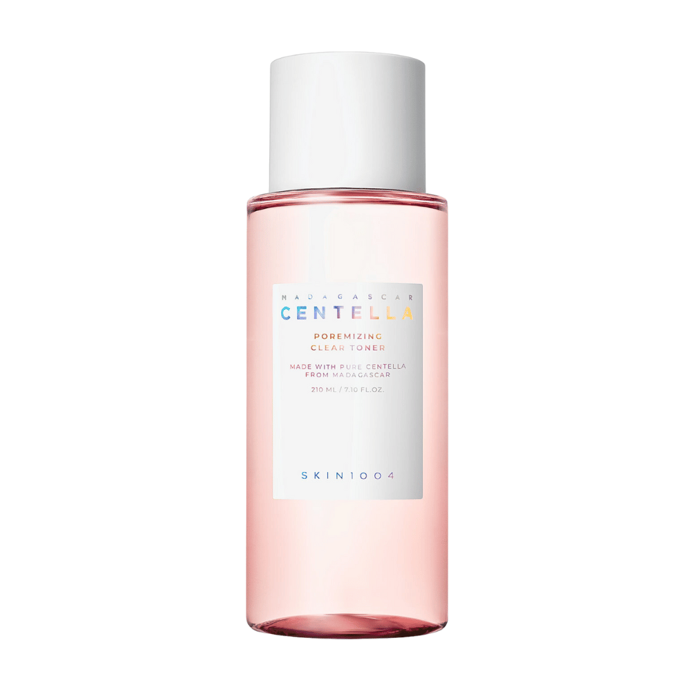 Una bottiglia con Madagascar Centella Poremizing Clear Toner, che è trasparente con una tonalità rosa. Il prodotto ha un tappo bianco e un'etichetta con il testo "Poremizing Clear Tonico viso" e "Made with Pure Centella from Madagascar." La bottiglia contiene 210 ml e dà una sensazione di freschezza e cura della pelle.