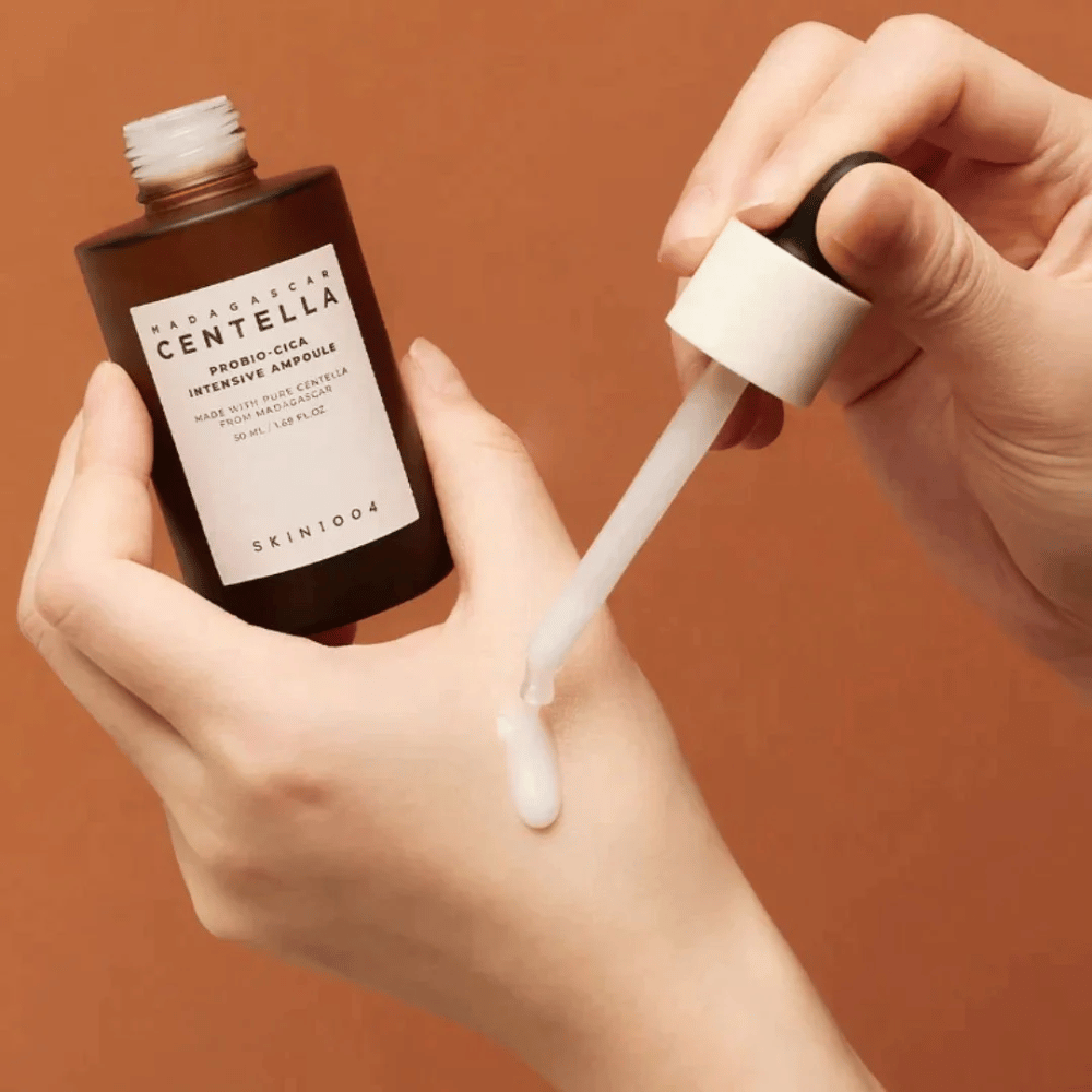 Mani che usano un contagocce per dosare "Madagascar Centella Probio-Cica Intensive Ampoule" da SKIN1004.