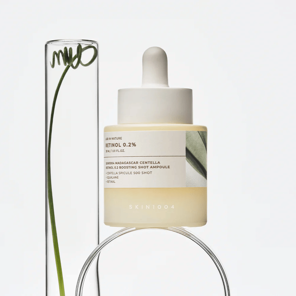 SKIN1004 Madagascar Centella Retinol 0.2 Boosting Shot Ampoule in un'immagine di lifestyle con elementi botanici – siero per il viso che supporta il rinnovamento della pelle e rinforza la barriera cutanea.