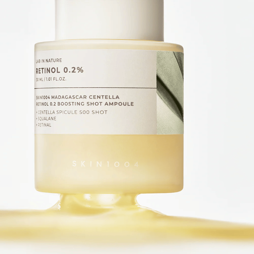 Primo piano di SKIN1004 Madagascar Centella Retinol 0.2 Boosting Shot Ampoule che mostra la consistenza leggermente gialla e setosa del siero al retinolo per il rinnovo notturno della pelle.