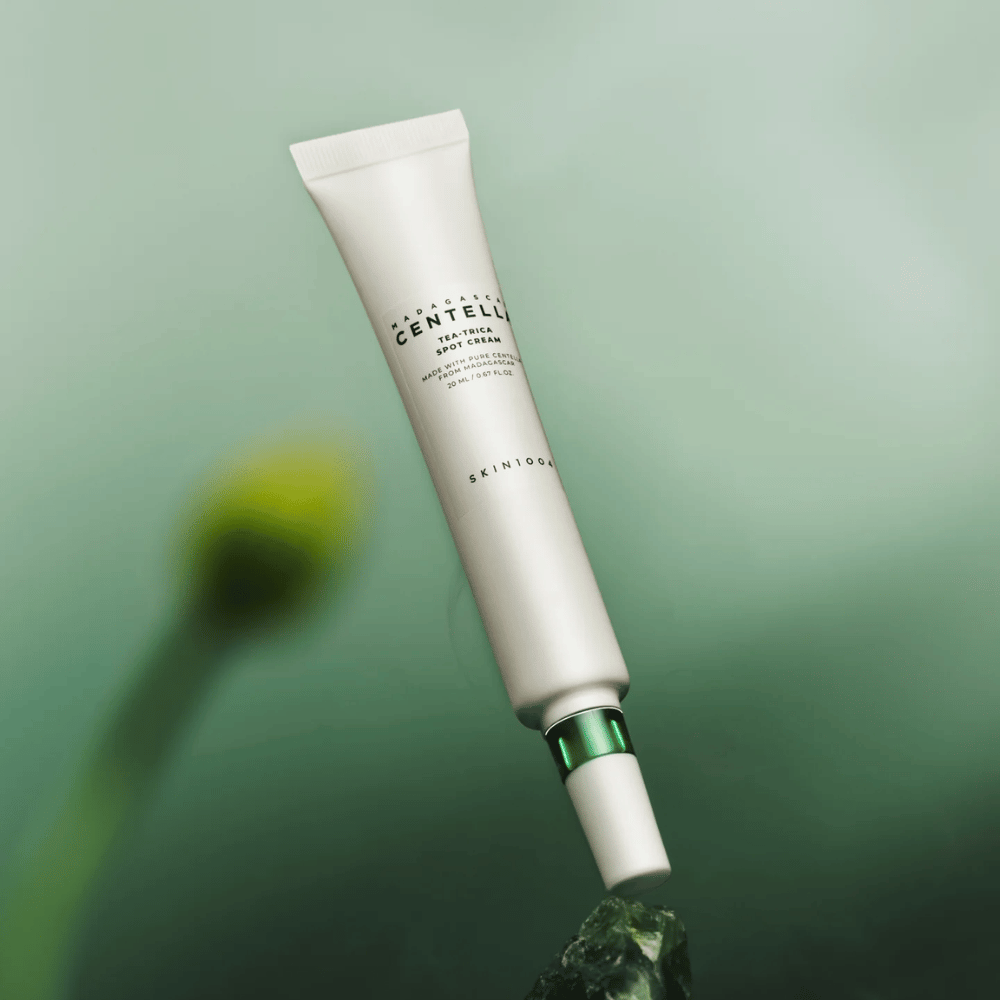 SKIN1004 Madagascar Centella Tea-Trica Spot Cream fluttuante su sfondo verde – trattamento efficace per punti treatment per pelle incline all'acne con centella del Madagascar.