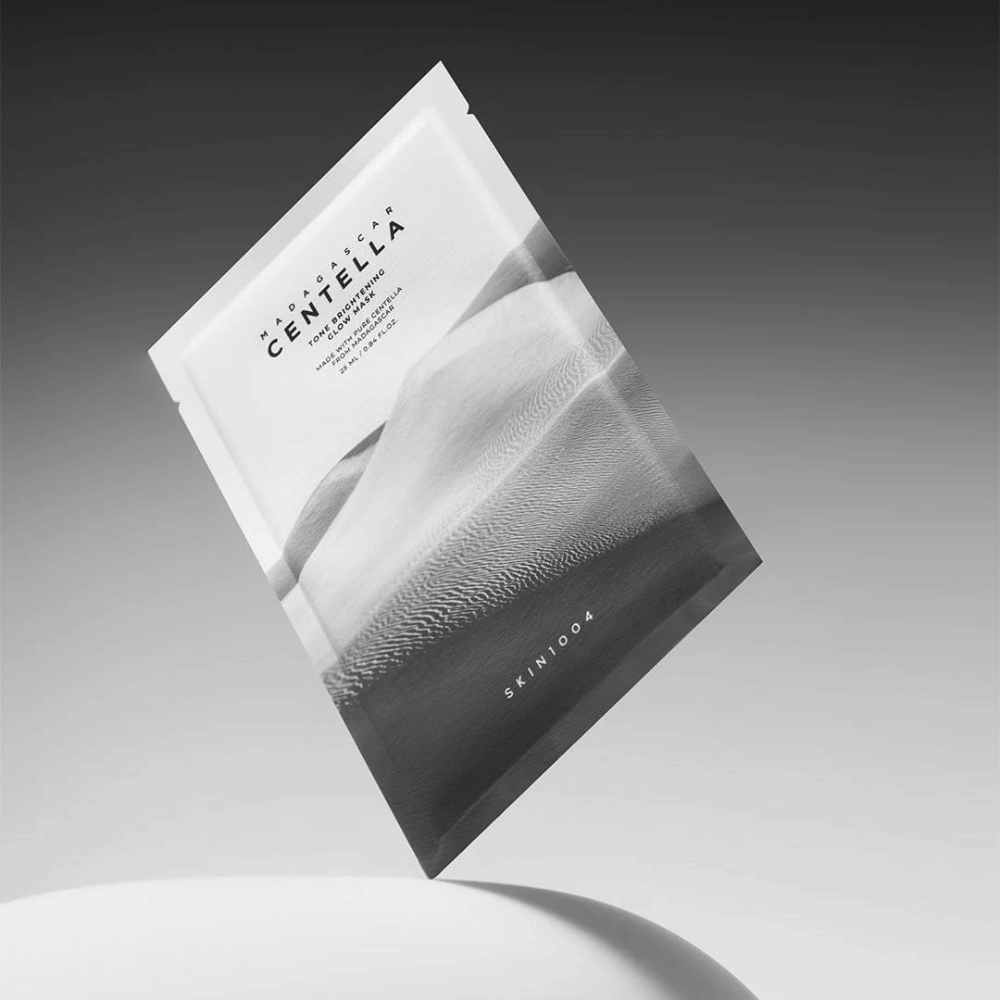 Confezione da Sheet mask di SKIN1004 sospesa su sfondo grigio con design minimalista.