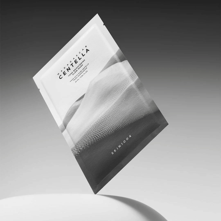 Confezione da Sheet mask di SKIN1004 sospesa su sfondo grigio con design minimalista.