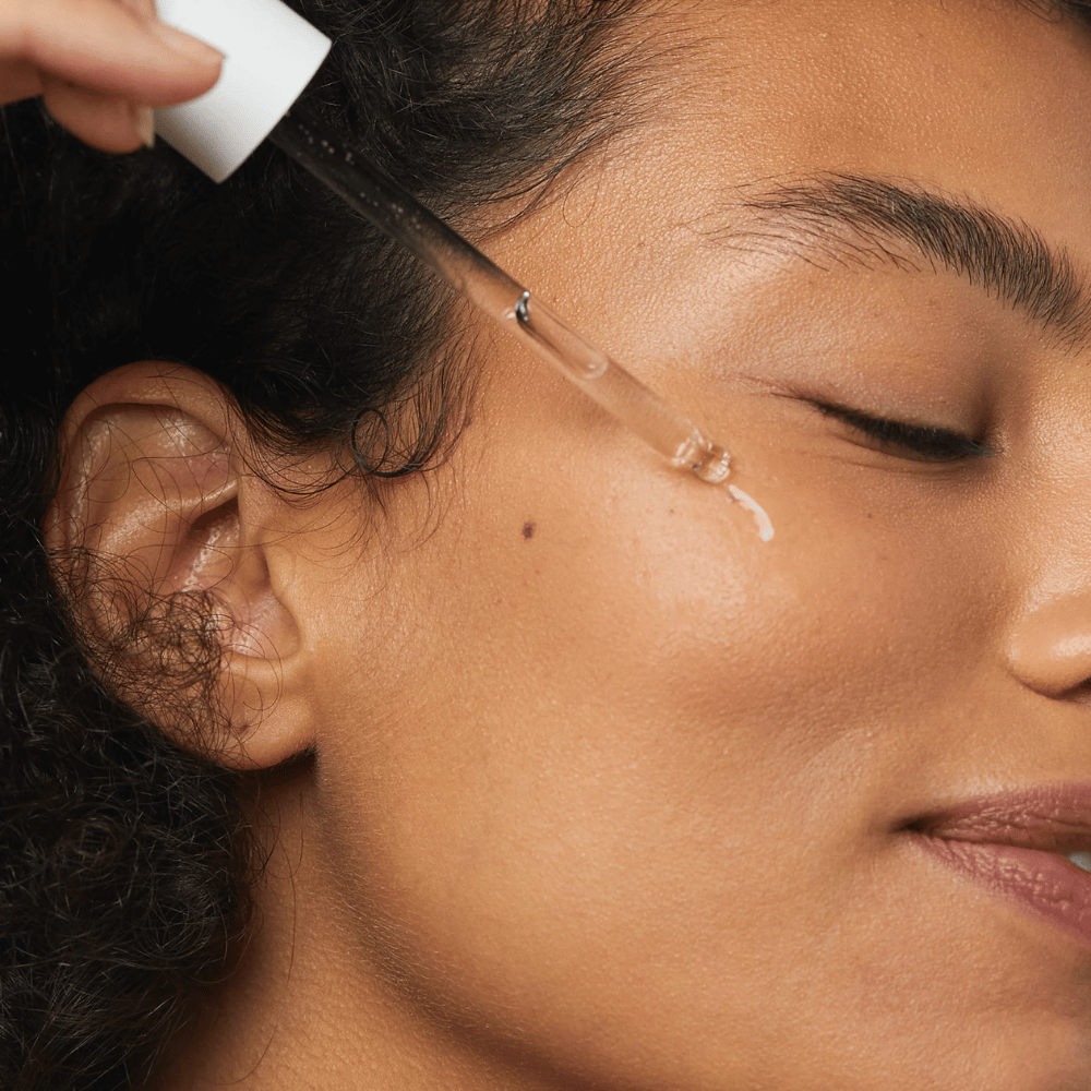 Donna applica Skin1004 Madagascar Centella Hyalu-Cica First Ampoule sulla guancia con una pipetta.