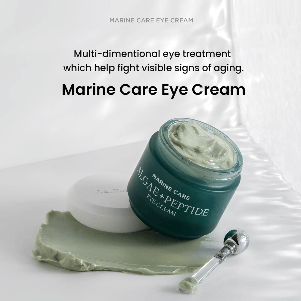 Heimish Marine Care Algae + Peptide Eye Cream in un barattolo aperto con crema verdastra. La crema è sparsa accanto al barattolo e un applicatore si trova accanto. Il prodotto combatte i segni dell'età e offre un'idratazione intensa.