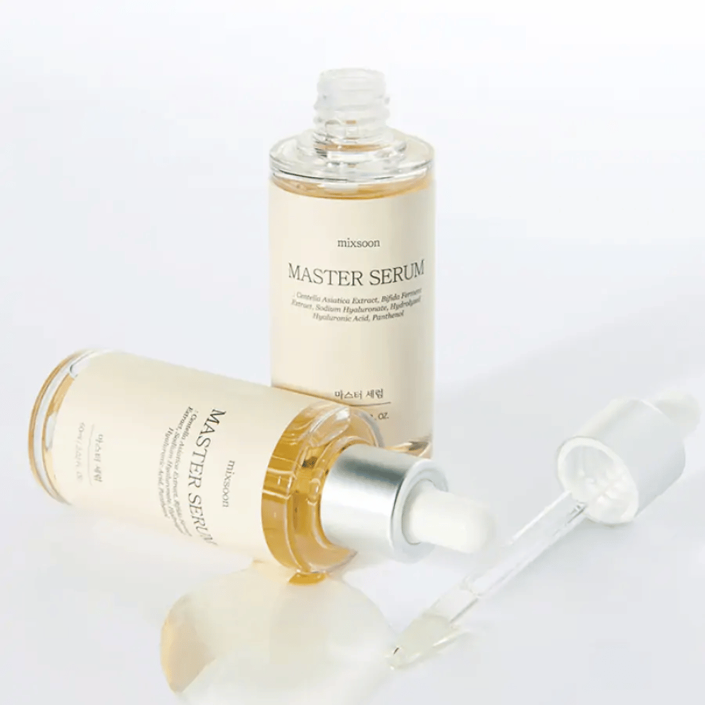 Due bottiglie Mixsoon Master Serum, una in piedi e una sdraiata con pipetta aperta, dove il siero è stato versato su una superficie bianca.