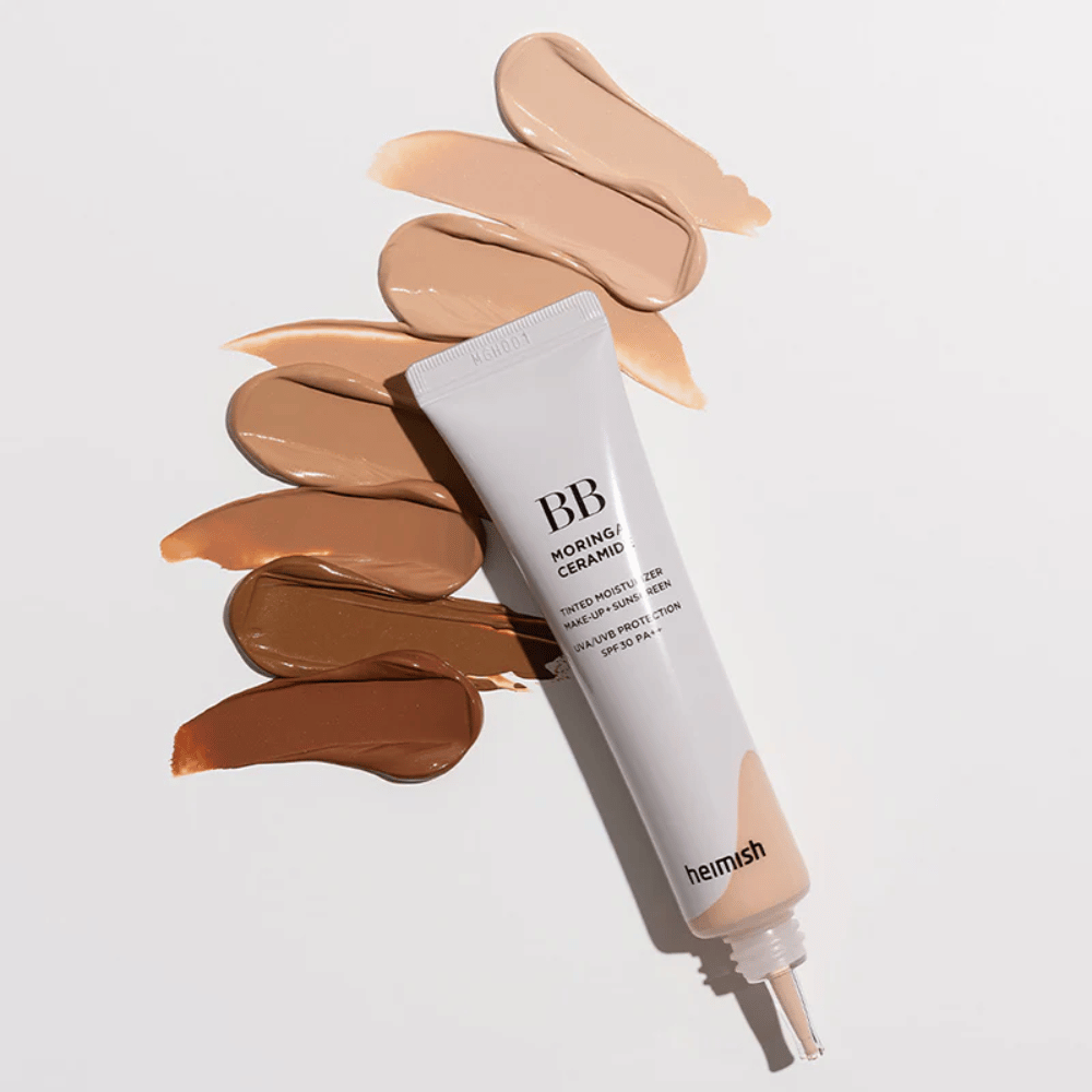 Heimish Moringa Ceramide BB Cream circondato da diversi campioni di tonalità in vari incarnati. L'immagine mostra l'ampia gamma di colori del prodotto e la consistenza cremosa che offre una copertura naturale e un incarnato uniforme.