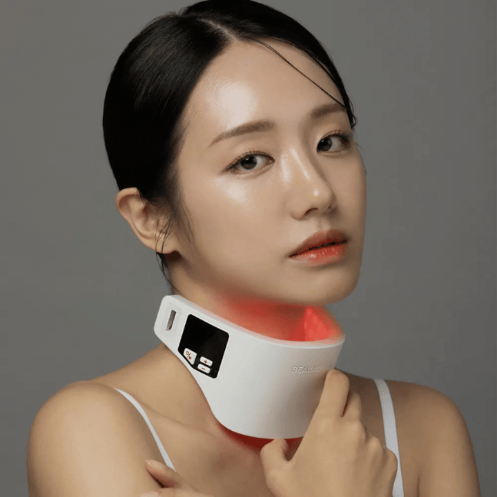 Una modella utilizza Beaund Neckcera intorno al collo. L'illuminazione LED rossa illustra il trattamento attivo mentre il dispositivo aderisce comodamente alla pelle.