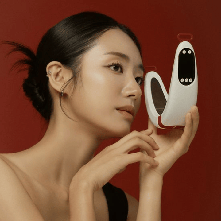 Una modella tiene Beaund Nmode Pro davanti al viso su uno sfondo rosso. L’immagine mette in evidenza il design elegante del dispositivo, il display digitale e il formato compatto.