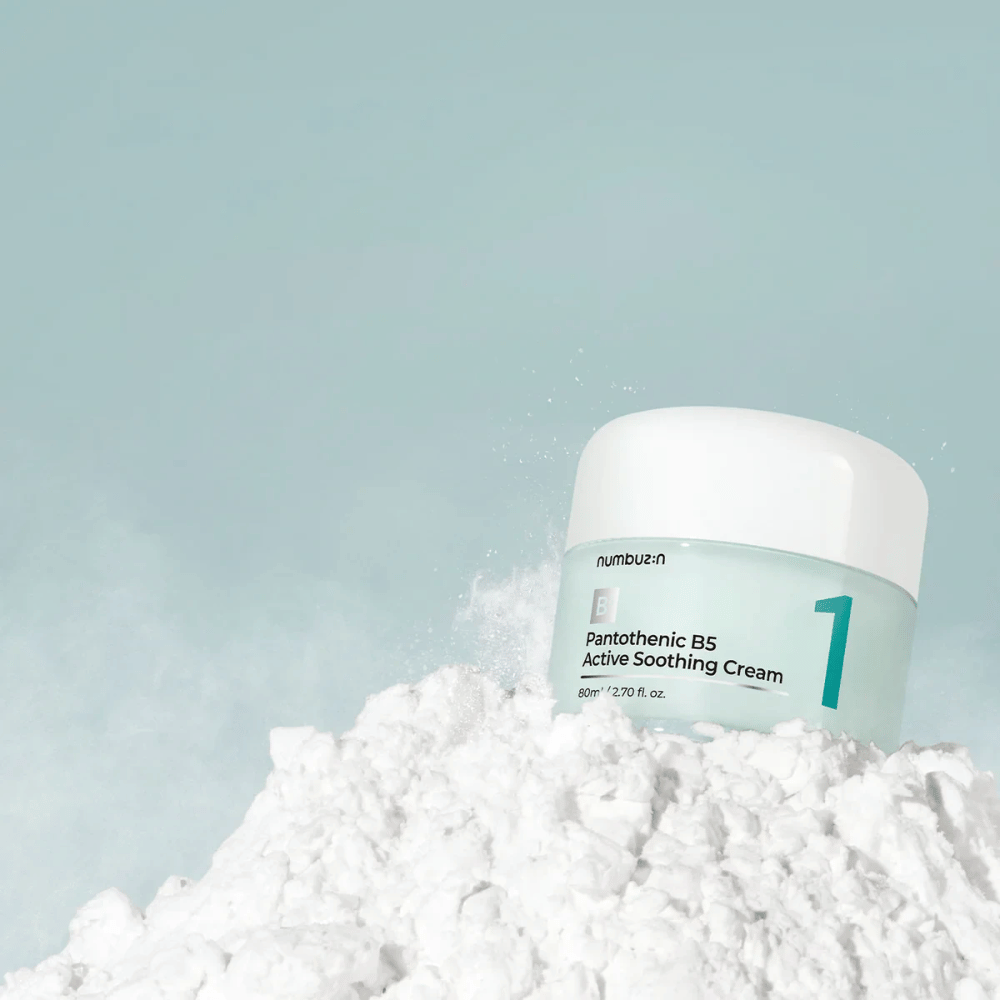 Numbuzin No.1 Pantothenic B5 Active Soothing Cream 80 ml in un barattolo verde chiaro con coperchio bianco, posizionato su un cumulo di polvere bianca su sfondo chiaro.