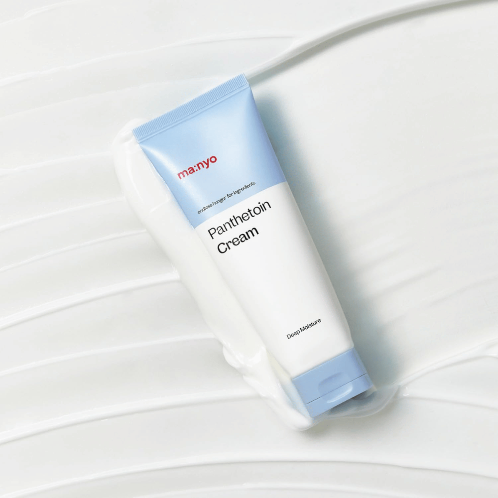 2. Ma:nyo Panthetoin Cream – crema viso idratante in tubo bianco e azzurro chiaro circondato da una texture cremosa su sfondo bianco