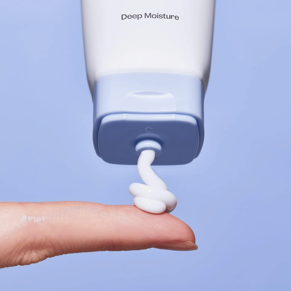 1. Ma:nyo Panthetoin Cream – primo piano di crema viso idratante bianca applicata da un tubo azzurro chiaro su un dito