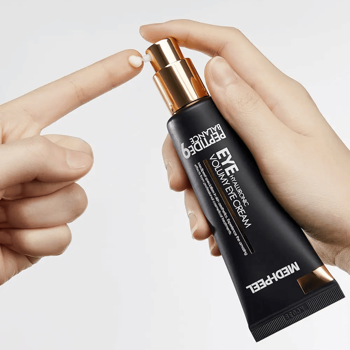 Applicazione di MEDI-PEEL Peptide 9 Hyaluronic Volumy Eye Cream sulla punta delle dita – idratante contorno occhi  con complesso peptidico che aiuta a ridurre le linee sottili e dona pelle rimpolpata.