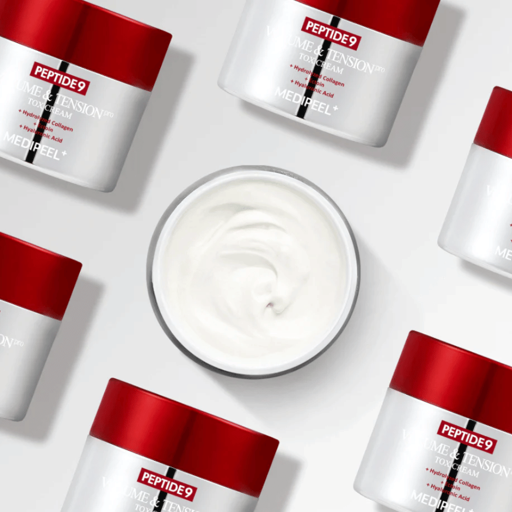 Diverse confezioni di MEDI-PEEL Peptide 9 Volume & Tension Tox Cream disposte su sfondo bianco. Il prodotto idrata intensamente e dona volume e luminosità alla pelle.