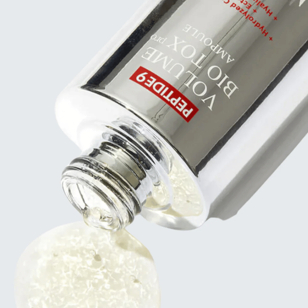 Primo piano di MEDI-PEEL Peptide 9 Volume Bio Tox Pro Ampoule mentre viene versato. La formula chiara con collagene, ectoina e acido ialuronico idrata in profondità.