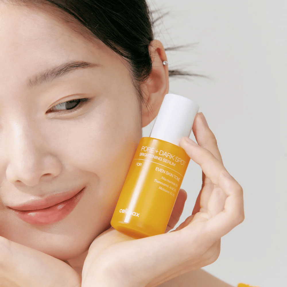 Modello tiene Celimax Pore + Dark Spot Brightening Serum vicino al viso, mostra una pelle radiosa.