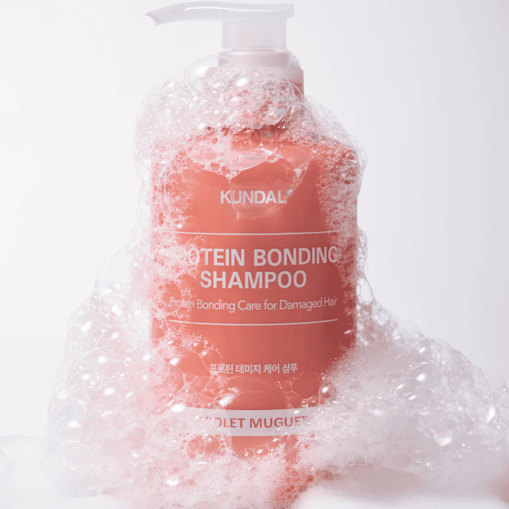 KUNDAL Protein Bonding Shampoo Violet Muguet coperto di abbondante schiuma, shampoo riparatore per capelli danneggiati.