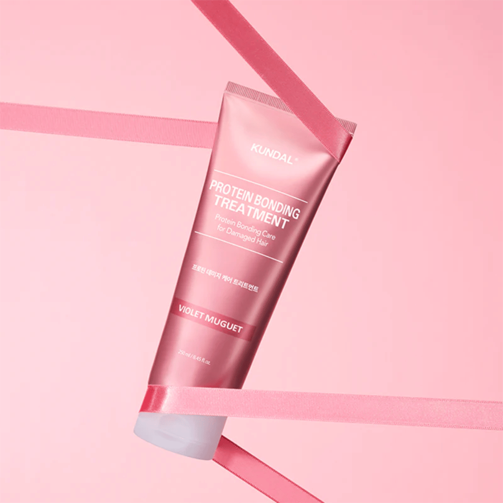 KUNDAL Protein Bonding Treatment Violet Muguet in tubo rosa 250 ml su sfondo rosa con nastri decorativi.
