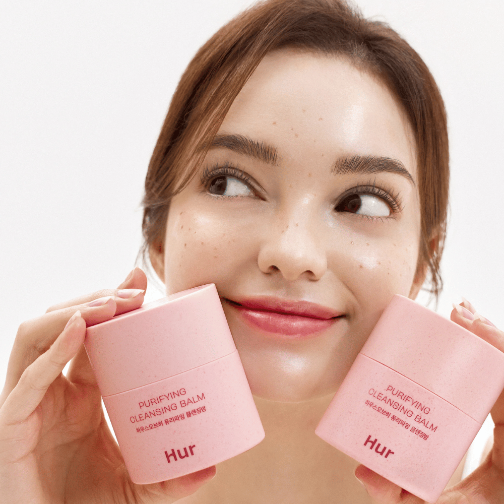 Modello tiene due barattoli Come Purifying Cleansing Balm. Delicato balsamo struccante adatto per la pelle sensibile e dona una sensazione fresca e idratata dopo la pulizia.