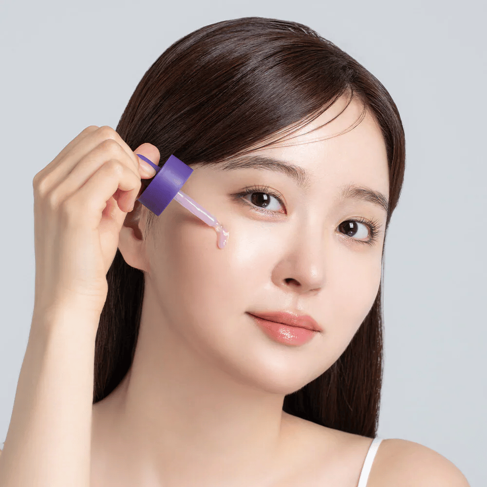Applicazione di Cellology Purple Carrot Pore Ampoule con contagocce sul viso per la cura dei pori e una texture della pelle più uniforme.