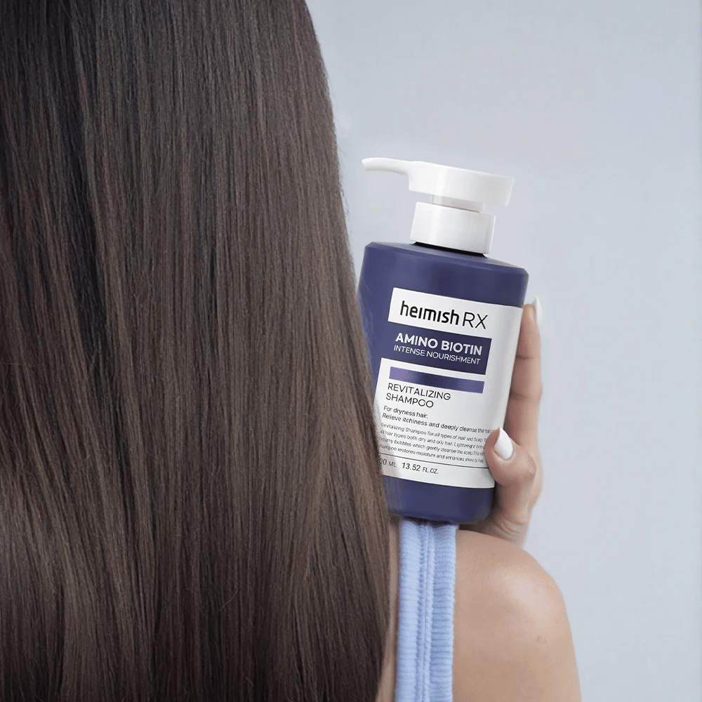 Heimish RX Amino Biotin Revitalizing Shampoo tenuto in mano contro capelli lunghi e lucenti – mostra il risultato di nutrimento intenso e idratazione per capelli secchi.